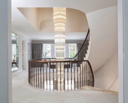 Landing view of Walnut continuous handrail and steel balustrade with central feature light