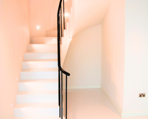 Custom-made sapele handrail and loose metal balusters on winder treads of a stylish staircase