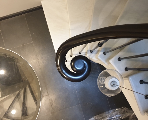 Hardwood volute monkey tail with steel rounded spindles to stone staircase