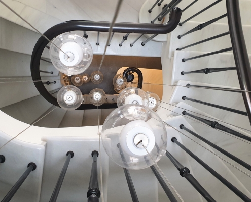 Continuous bespoke timber handrail with steel rounded spindles to stone spiral staircase