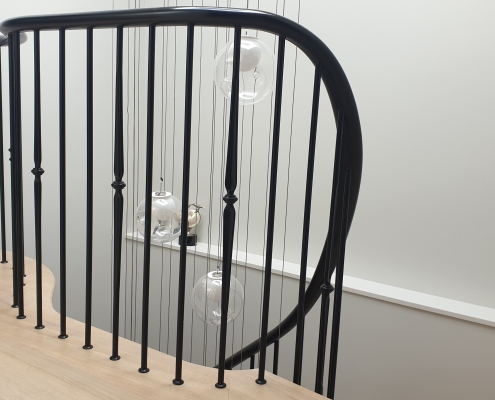 Sweeping bespoke timber handrail on landing with steel rounded spindles