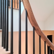 Tapered Black rounded spindles fixed to rising timber handrail