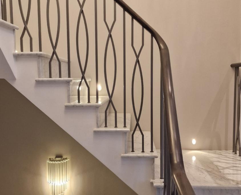 Traditional-style timber balustrade with dark handrail and wall lights on a period staircase