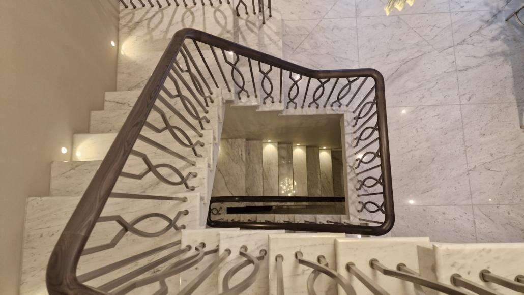 Looking down a stairwell at a bespoke balustrade with sculptural branch-pattern metalwork and dark handrail