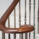 Sweeping volute scroll feature on stone staircase in Black Walnut.