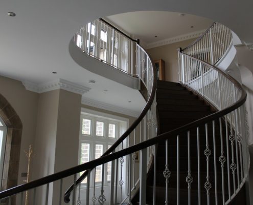 Curved staircase with bespoke timber handrail & steel spindles either side