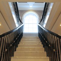 Black handrails either side of stone staircase with matching coloured balustrade