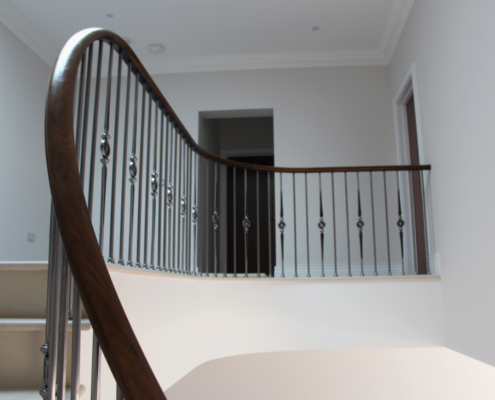 Stone clad stair Surrey Design team Stonemasons Steel spindles Black walnut handrails Core rail Steep pitch Precision drilling 16.5mm holes Perfect fit Handrail finish Lightfast stain French polished