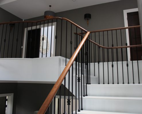 Walnut handrails & steel spindles to stone contemporary staircase going to landing