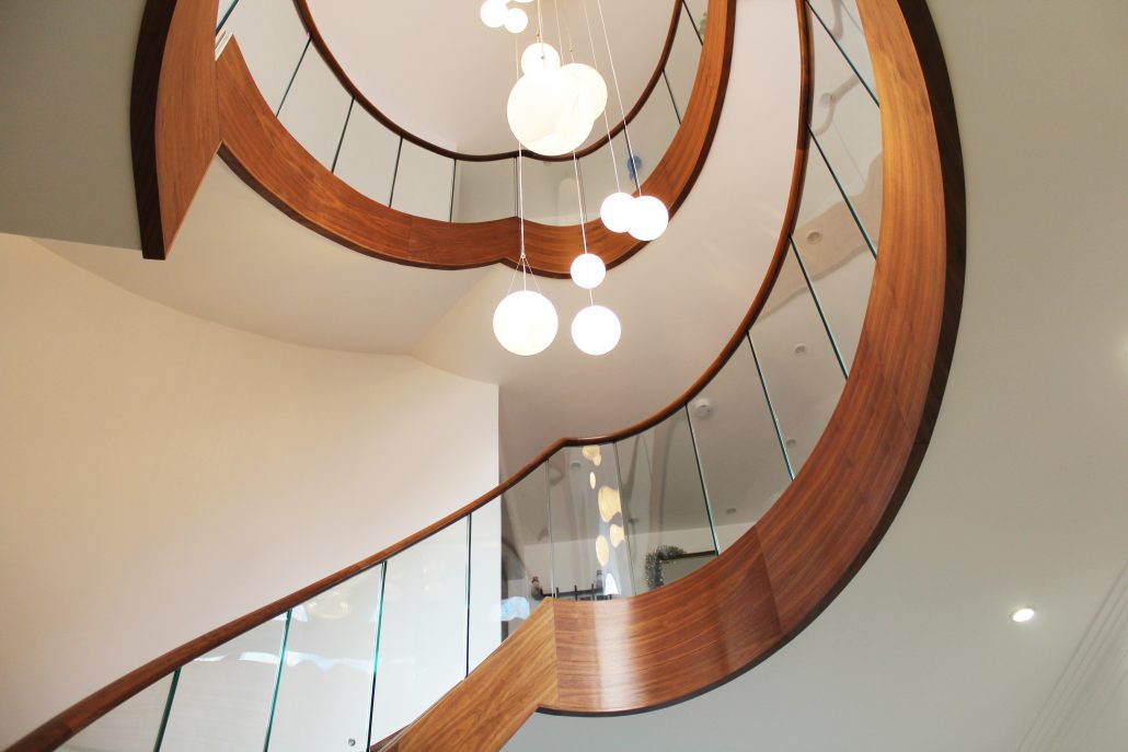 elliptical staircase, black walnut, curved glass balustrade, continuous handrails, precision surveying, millimeter-perfect, Hertfordshire, Christmas decorations, Santa Claus, bespoke staircase.