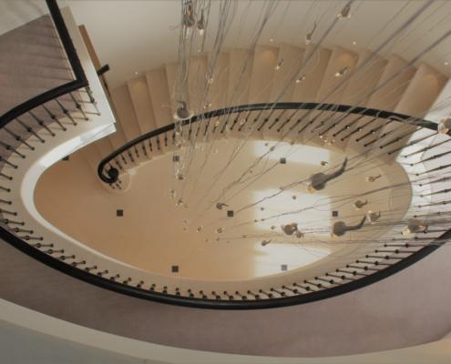 Hawk eye view of stone curved staircase with matching coloured timber handrail and steel balustrade