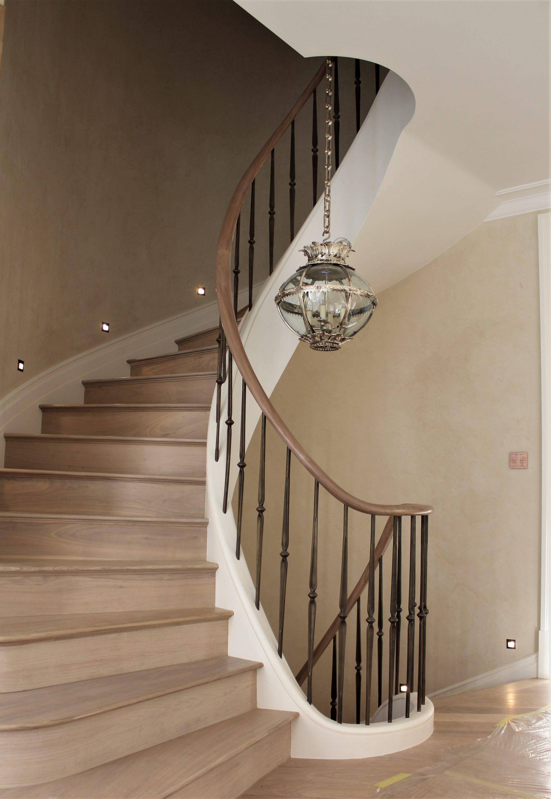 Helical oak handrail section rising up staircase and brass finished spindles