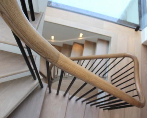 Elegant sweeping oak handrail Tapered steel spindles Unique contemporary staircase Six-storey luxury home Bespoke balustrade Steel spindles turned on a lathe Individual fixing of spindles No need for an ugly metal rail 3D model of the staircase Optimum precision French polished oak handrails Oak flooring Contractors: Bancroft Heath and Layzell Architects Continuous handrail Bespoke metal balustrade