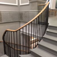 Oak handrails with rising helical section, Black spindles, stone staircase in Grey