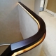 Curved dark tone timber handrail on landing