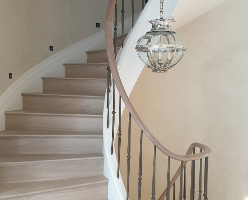 Helical oak handrail section rising up staircase and brass finished spindles