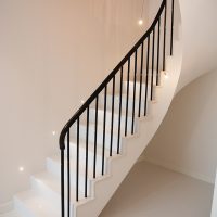 Stone curved staircase with Black timber handrail & Black steel rounded spindles