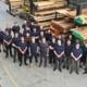 The Handrail Creations team in navy uniforms in the workshop beside stacked timber