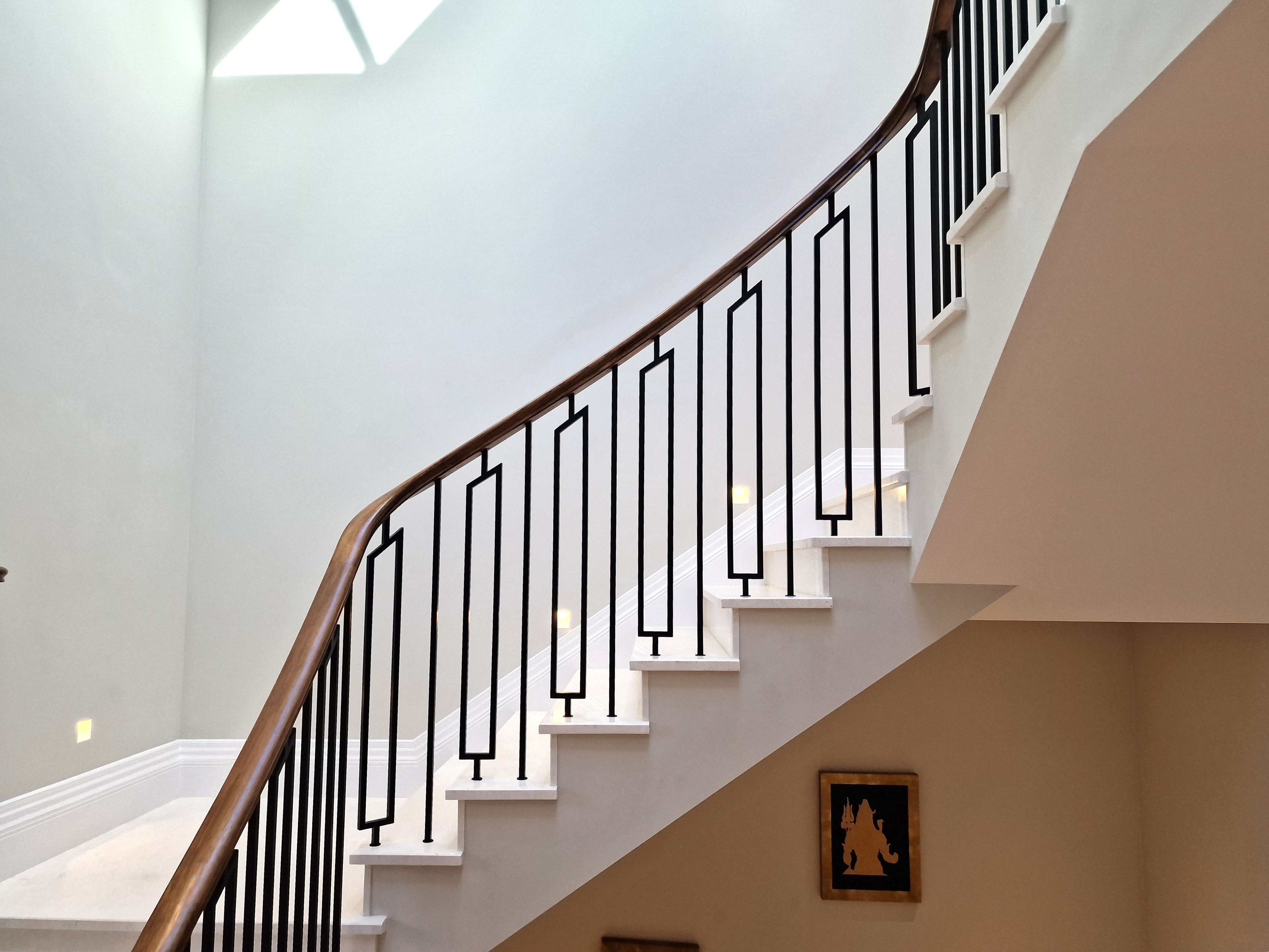 Oak staircase with slim black metal balustrade in a residential hallway