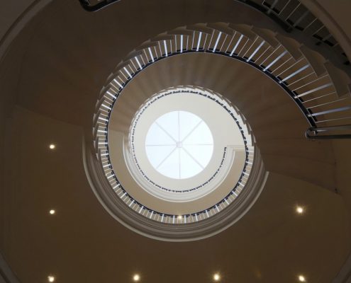 Upward view of spiral staircase with continuous bespoke handrail leather wrapped and steel balustrade