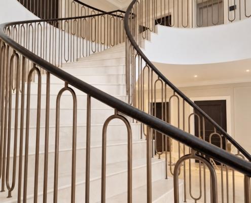Close up of French polished oak handrail and bronze hoop spindles on the curved flight