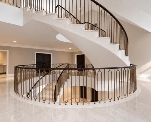Oval landing balustrade and helical stair viewed from the first floor, bronze spindles and oak rail