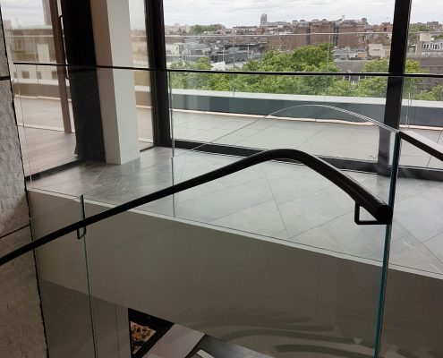 Spiral staircase with glass balustrade and Black timber helical rising handrails